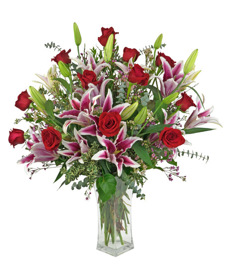 Fabulous stargazer lilies with long stemmed red roses in a clear glass vase.