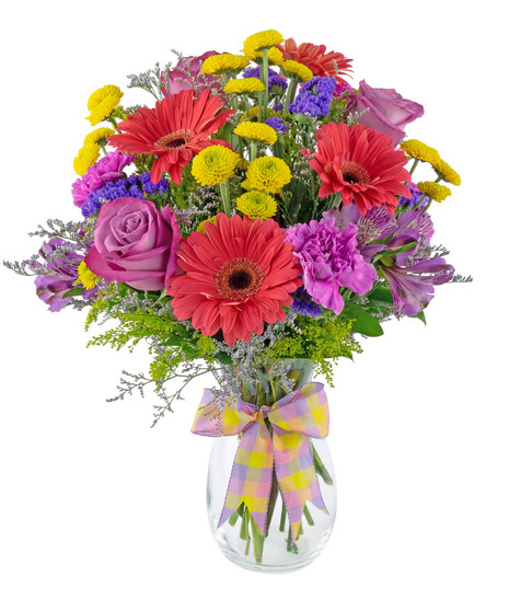 Bright and colorful flowers are arranged in a clear glass  vase. 