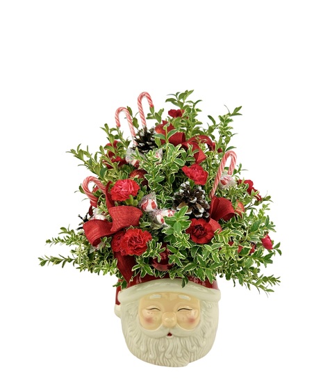 Santa head that has boxwood greens, red flowers and peppermint candies.