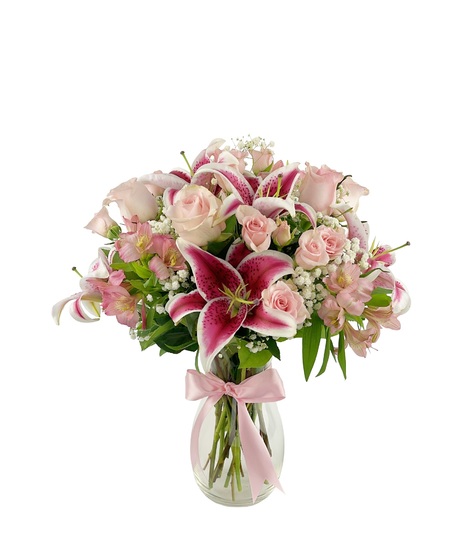 Shades of pink in a clear vase with a satin ribbon tied around the vase.