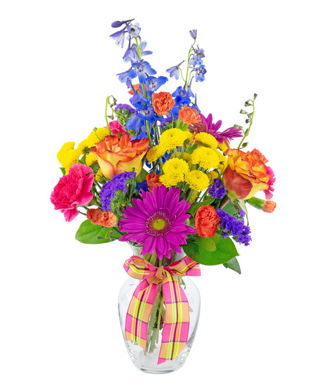 Hot pink, orange, yellow and purple gerbers, delphinium, roses and carnations in a clear glass vase tied with a pretty bow.