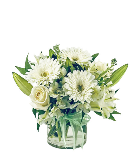 White oriental lilies surrounded by roses, gerbera daisies, alstromeria and stock in hues of white and green in a clear glass cube vase.