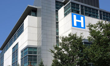 A modern hospital building displays a large blue 